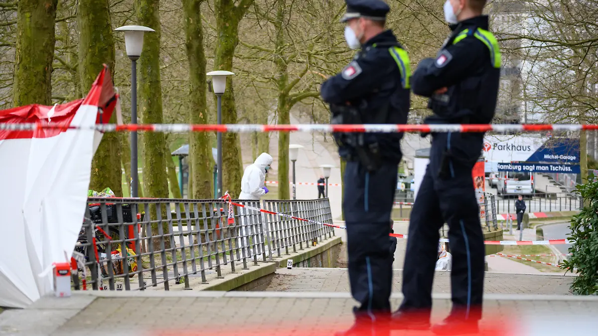 ARCHIV - 28.03.2022, Hamburg: Ermittler und Polizisten stehen an dem mit Flatterband abgesperrten Tatort. Ein Passant hatte am 28. März am frühen Morgen in Hamburg auf der Michelwiese einen leblosen Mann gefunden und die Polizei alarmiert. Nun muss sich ein 47-Jähriger in einem Mordprozess vor dem Landgericht Hamburg verantworten. ( zu dpa: «Prozess um Mord am Hamburger Michel - 47-Jähriger vor Gericht») Foto: Jonas Walzberg/dpa +++ dpa-Bildfunk +++