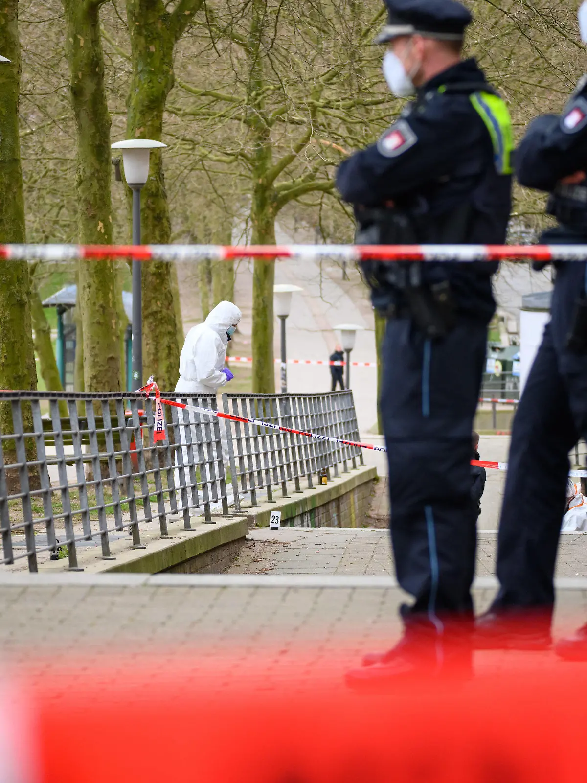 ARCHIV - 28.03.2022, Hamburg: Ermittler und Polizisten stehen an dem mit Flatterband abgesperrten Tatort. Ein Passant hatte am 28. März am frühen Morgen in Hamburg auf der Michelwiese einen leblosen Mann gefunden und die Polizei alarmiert. Nun muss sich ein 47-Jähriger in einem Mordprozess vor dem Landgericht Hamburg verantworten. ( zu dpa: «Prozess um Mord am Hamburger Michel - 47-Jähriger vor Gericht») Foto: Jonas Walzberg/dpa +++ dpa-Bildfunk +++