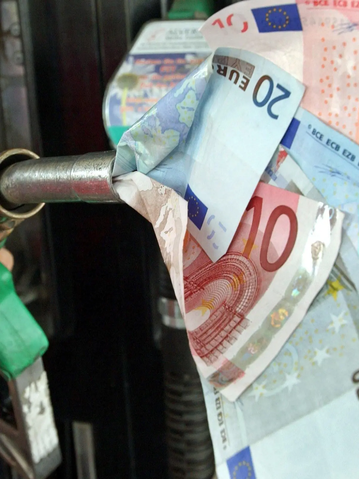 Eine Zapfpistole "saugt" Geldscheine ein (Symbolbild aufgenommen am 10.5.2004 in Frankfurt an der Oder). Der Benzinpreis war zuletzt an deutschen Tankstellen auf ein Rekordhoch von 1,20 Euro für den Liter Super gestiegen. Den schnelleren Anstieg der Benzinpreise gegenüber dem Ölpreis führen Experten auf einen Engpass bei Raffinerien zurück, die Benzin herstellen. Der Benzinpreis an der Tankstelle besteht zu rund 70 Prozent aus Steuern und Abgaben. Die Mineralöl- und Ökosteuern betragen fest 65,5 Cent je Liter und verändern sich nicht, wenn Preise steigen. Auf Preis und Steuern werden 16 Prozent Mehrwertsteuer berechnet. Um den Benzinpreis auf einen Euro je Liter zu senken - wie teils gefordert - müsste der Staat auf rund 13 Milliarden Euro Einnahmen verzichten.