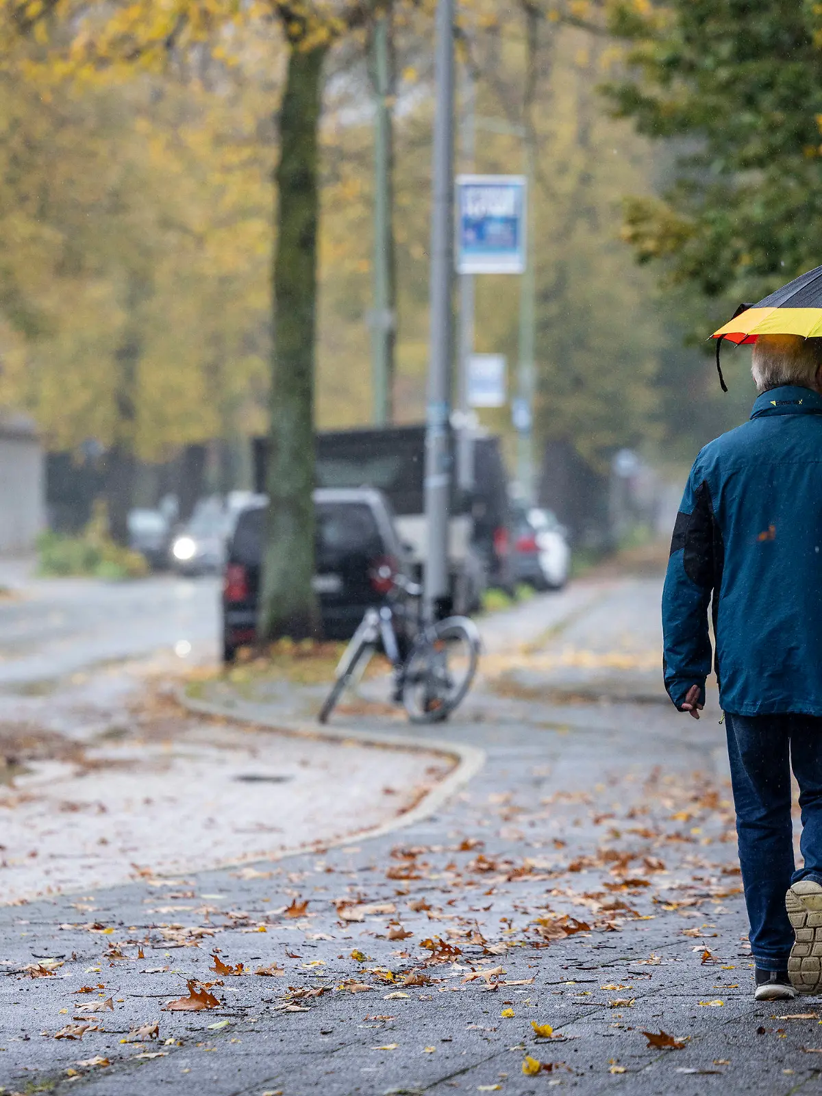 05.11.2023, Nordrhein-Westfalen, Duisburg: Passanten mit Regenschirm sind im Regen auf dem Gehweg unterwegs. Viele Wolken mit Regen und Wind: Auch in der neuen Woche bleibt das Wetter in Nordrhein-Westfalen wechselhaft. Immer mal wieder seien am Montag und Dienstag Schauer zu erwarten, sagte eine Meteorologin des Deutschen Wetterdienstes (DWD) am Sonntag in Essen. Dazu gebe es vor allem im Bergland starke bis stürmische Windböen. Die Sonne komme nur vereinzelt raus, Auflockerungen seien eher selten - bei milden Temperaturen von maximal 11 bis 14 Grad. Foto: Christoph Reichwein/dpa +++ dpa-Bildfunk +++