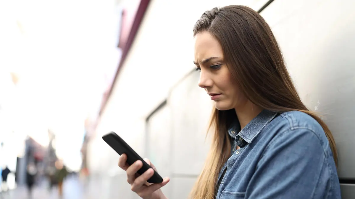  Sad woman checking smart phone content in the street ,model released, Symbolfoto PUBLICATIONxINxGERxSUIxAUTxONLY Copyright: xAntonioGuillemx Panthermedia26834141