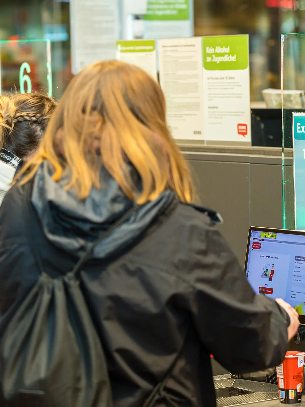 Kundinnen scannen und bezahlen ihre Einkäufe an einer Selbstbedienungskasse in einem Lebensmittelsupermarkt.