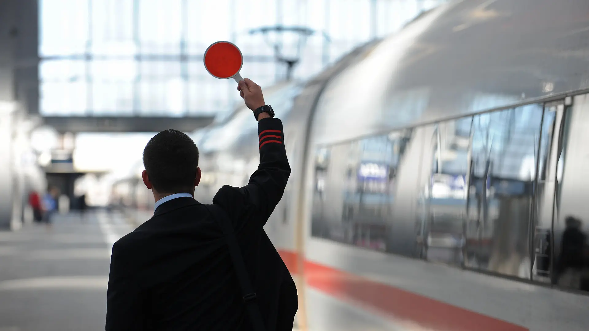 Ein Zugbegleiter gibt am Freitag (07.09.2012) am Hauptbahnhof in München (Oberbayern) das Signal zur Abfahrt. Der flächendeckende Streik der Lufthansa-Flugbegleiter trifft nach Angaben des Unternehmens mehr als 100 000 Passagiere. Foto: Andreas Gebert dpa/lby ++
