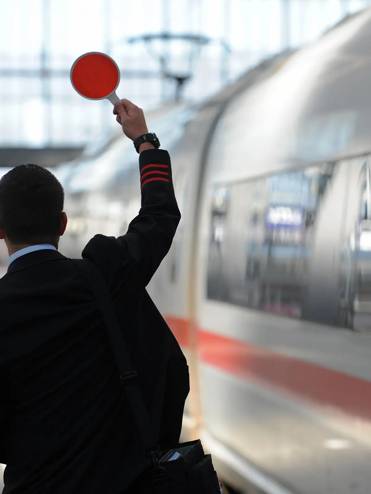 Ein Zugbegleiter gibt am Freitag (07.09.2012) am Hauptbahnhof in München (Oberbayern) das Signal zur Abfahrt. Der flächendeckende Streik der Lufthansa-Flugbegleiter trifft nach Angaben des Unternehmens mehr als 100 000 Passagiere. Foto: Andreas Gebert dpa/lby ++