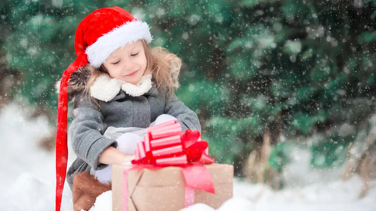 Cute little girl with christmas box gift in winter day