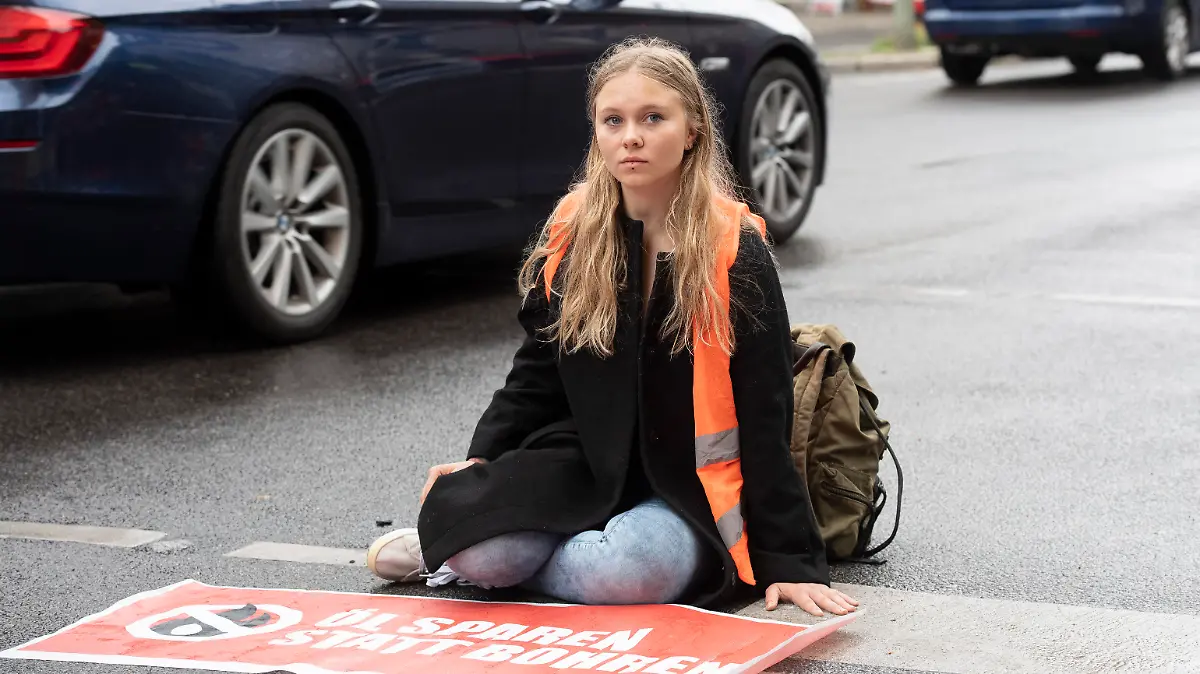 Klimaschutz-Demonstrantin Aimée van Baalen (22) sitzt unweit der Wetraße auf der Fahrbahn. Mitglieder der Gruppe "Letzte Generation" haben nach einer längeren Pause heute wieder ahlreiche Straßen in der Stadt blockiert.