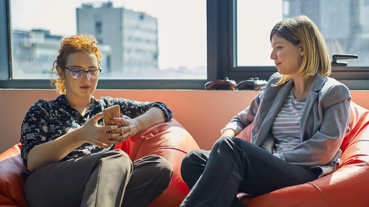 Colleagues with cell phones sitting in bean bags in office lounge model released Symbolfoto property released PUBLICATIONxINxGERxSUIxAUTxHUNxONLY ZEDF00987  