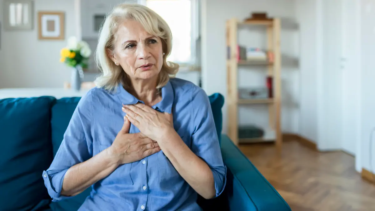 Senior Woman Suffering From Chest Pain While Sitting on Sofa at Home. Old Age, Health Problem, Vision and People Concept. Heart Attack Concept. Elderly Woman Suffering From Chest Pain Indoor