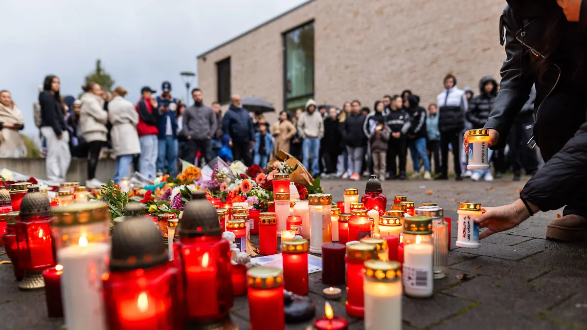 10.11.2023, Baden-Württemberg, Offenburg: Rund 200 trauernde Menschen stehen während einer stillen Gedenkveranstaltung rund um Blumen und Kerzen, die vor einer Schule liegen. Am gestrigen Donnerstag hatte in einer Offenburger Schule ein Schüler einen anderen Schüler erschossen, das Opfer ist später seinen Verletzungen erlegen. Foto: Philipp von Ditfurth/dpa +++ dpa-Bildfunk +++