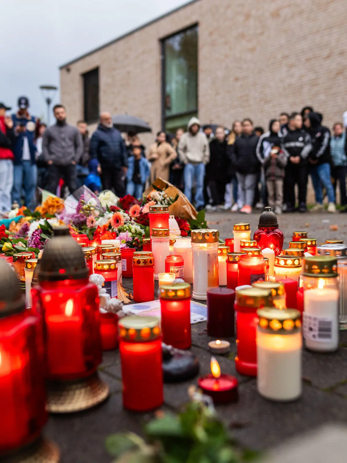 10.11.2023, Baden-Württemberg, Offenburg: Rund 200 trauernde Menschen stehen während einer stillen Gedenkveranstaltung rund um Blumen und Kerzen, die vor einer Schule liegen. Am gestrigen Donnerstag hatte in einer Offenburger Schule ein Schüler einen anderen Schüler erschossen, das Opfer ist später seinen Verletzungen erlegen. Foto: Philipp von Ditfurth/dpa +++ dpa-Bildfunk +++