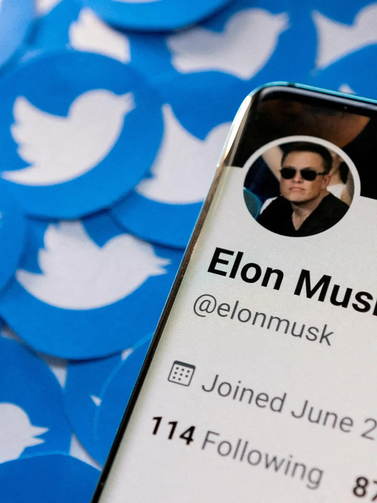 FILE PHOTO: Elon Musk's Twitter profile is seen on a smartphone placed on printed Twitter logos in this picture illustration taken April 28, 2022. REUTERS/Dado Ruvic/Illustration/File Photo
