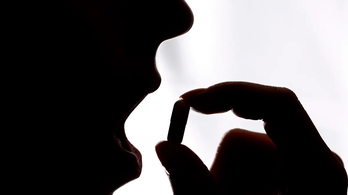 Junge Frau nimmt eine Tablette, Kapsel, ein || Modellfreigabe vorhanden