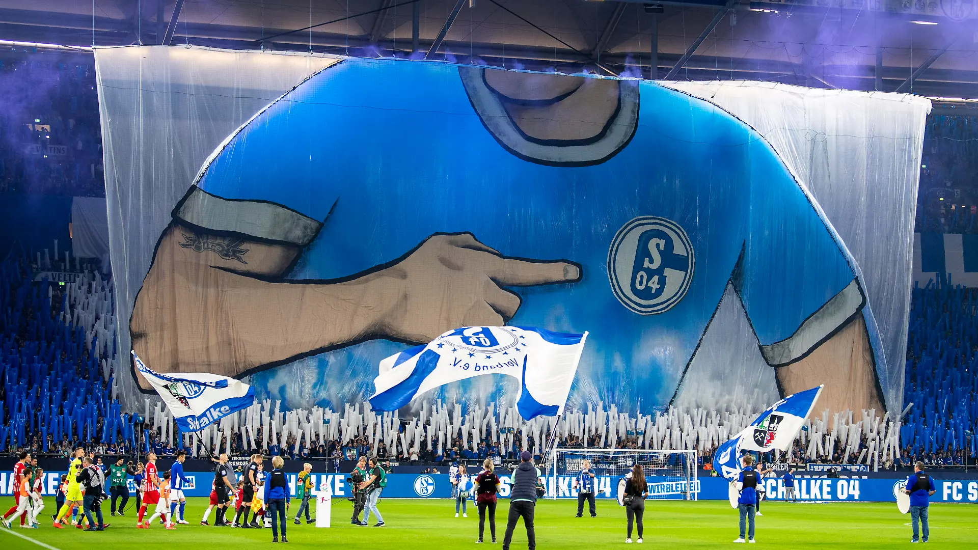Fußball: Bundesliga, FC Schalke 04 - SC Freiburg, 12. Spieltag, Veltins Arena: Die Schalker Fans zeigen beim Einmarsch der Mannschaft eine Choreographie. Pyrotechnik verwandelt das vormals weiße Trikot in ein blaues Shirt.