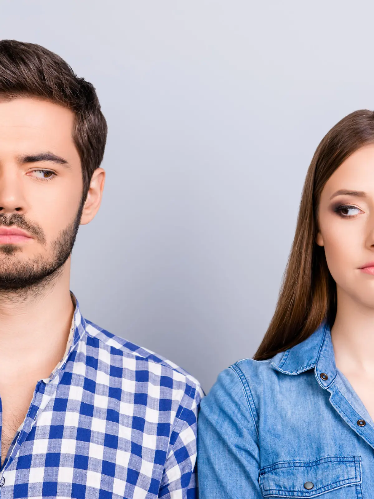 Mistrust and cheat problems. Annoyed couple is ignoring each other, but spy each other secretly, they stand on pure background in casual shirts