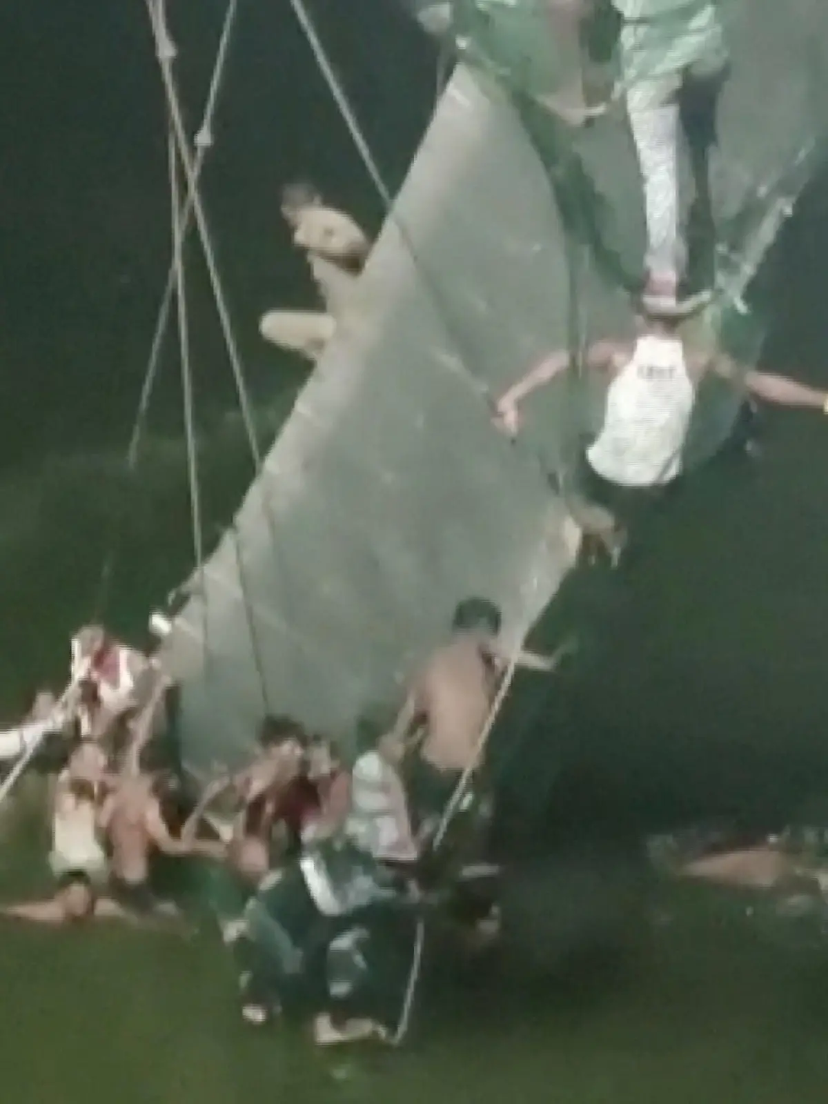 People cling on to the collapsed suspension bridge in Morbi, India October 30, 2022 in this screen grab obtained from a video. ANI/ Handout via REUTERS    THIS IMAGE HAS BEEN SUPPLIED BY A THIRD PARTY INDIA OUT. NO COMMERCIAL OR EDITORIAL SALES IN INDIA