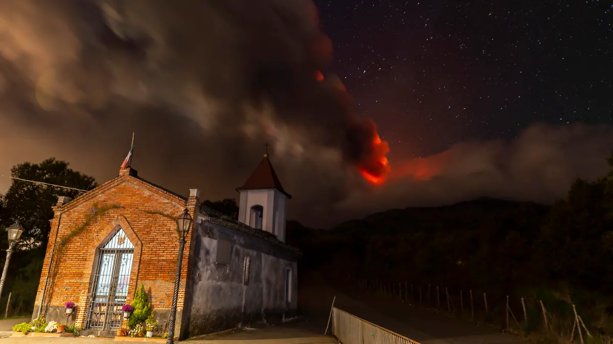 12.11.2023, Italien, Sant'Alfio: Rauchschwaden des Vulkans Ätna, gesehen von der Kirche Magazzeni in der Nähe des Dorfes Sant'Alfio. Europas größter aktiver Vulkan Ätna hat am Sonntag (12.11.2023) große Mengen glühende Lava in den Himmel gespuckt. Foto: Salvatore Allegra/AP/dpa +++ dpa-Bildfunk +++