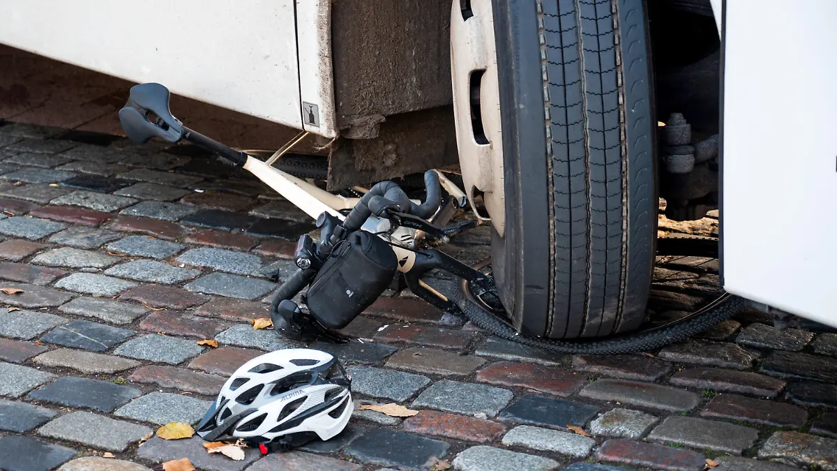 18.11.2023, Hamburg: Ein Fahrrad liegt nach einem Unfall unter dem Reifen eines Reisebusses. Beim Rechtsabbiegen hat der Bus einen Radfahrer übersehen und schwer verletzt. Der Radfahrer wurde ins Krankenhaus gebracht, wo er wenig später seinen Verletzungen erlegen sei. Foto: Daniel Bockwoldt/dpa +++ dpa-Bildfunk +++