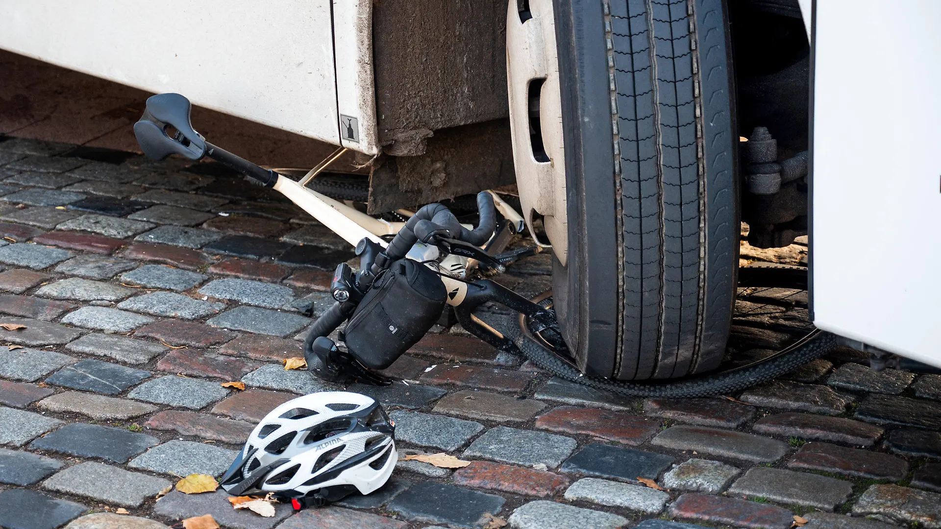 18.11.2023, Hamburg: Ein Fahrrad liegt nach einem Unfall unter dem Reifen eines Reisebusses. Beim Rechtsabbiegen hat der Bus einen Radfahrer übersehen und schwer verletzt. Der Radfahrer wurde ins Krankenhaus gebracht, wo er wenig später seinen Verletzungen erlegen sei. Foto: Daniel Bockwoldt/dpa +++ dpa-Bildfunk +++