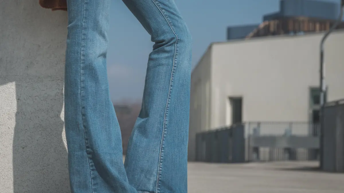 Detail of a girl wearing flared jeans and posing in an urban context