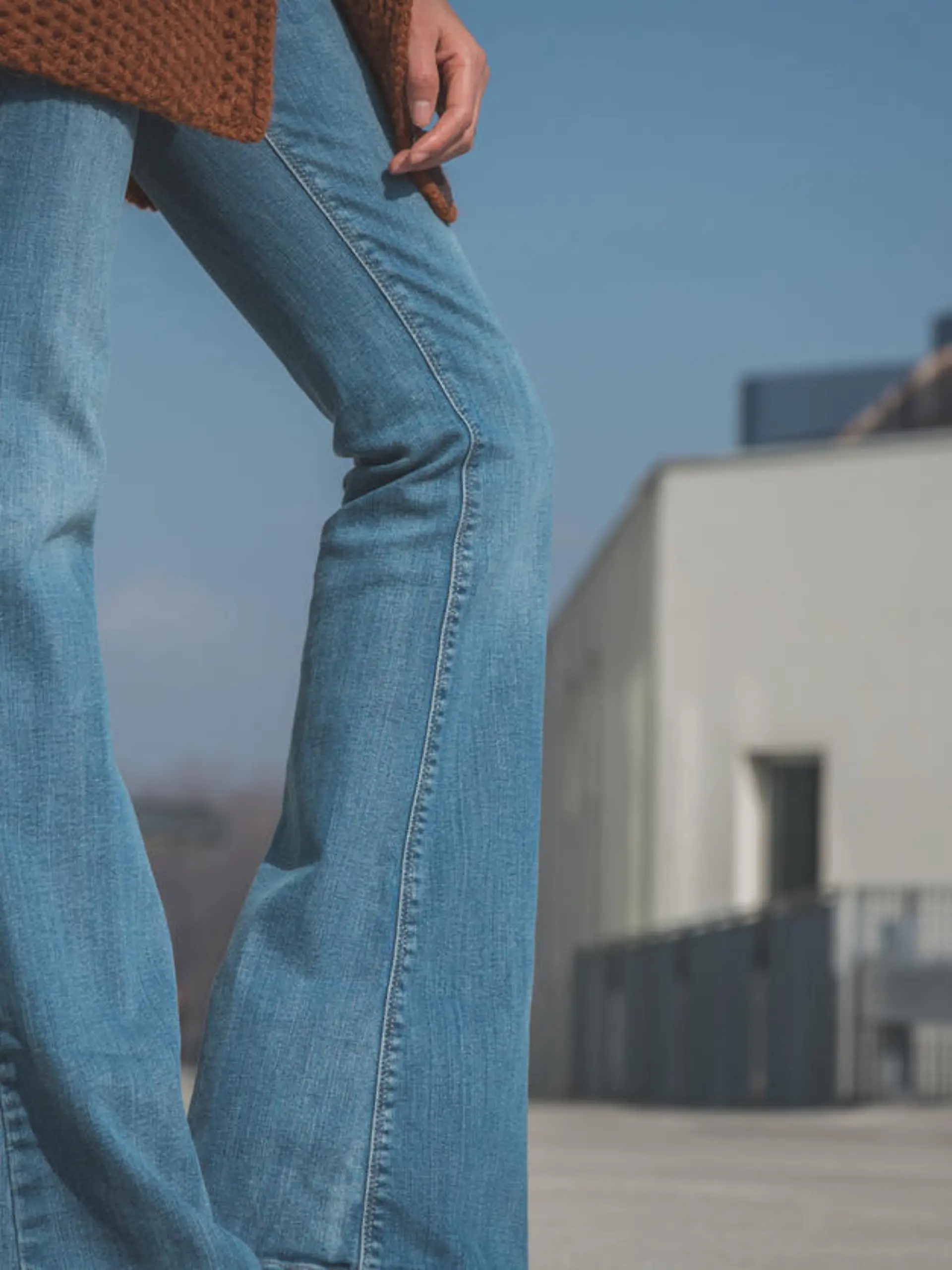 Detail of a girl wearing flared jeans and posing in an urban context