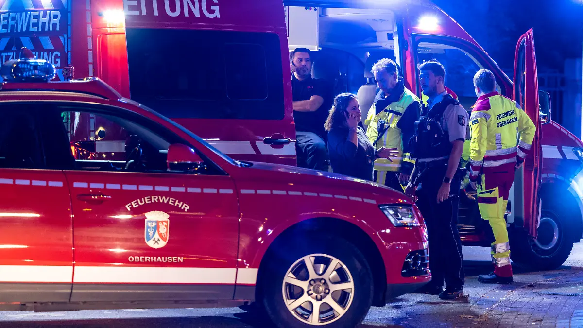 29.10.2022, Nordrhein-Westfalen, Oberhausen: Feuerwehrleute besprechen sich vor einem Fast-Food-Restaurant am Fahrzeug der Einsatzleitung, nachdem im Außenbereich der Filiale Schüsse gefallen waren. Drei Menschen wurden verletzt. Der Täter sei auf der Flucht, teilte ein Polizeisprecher mit. Die Hintergründe der Tat sind dem Sprecher zufolge noch unklar. Foto: Christoph Reichwein/dpa +++ dpa-Bildfunk +++