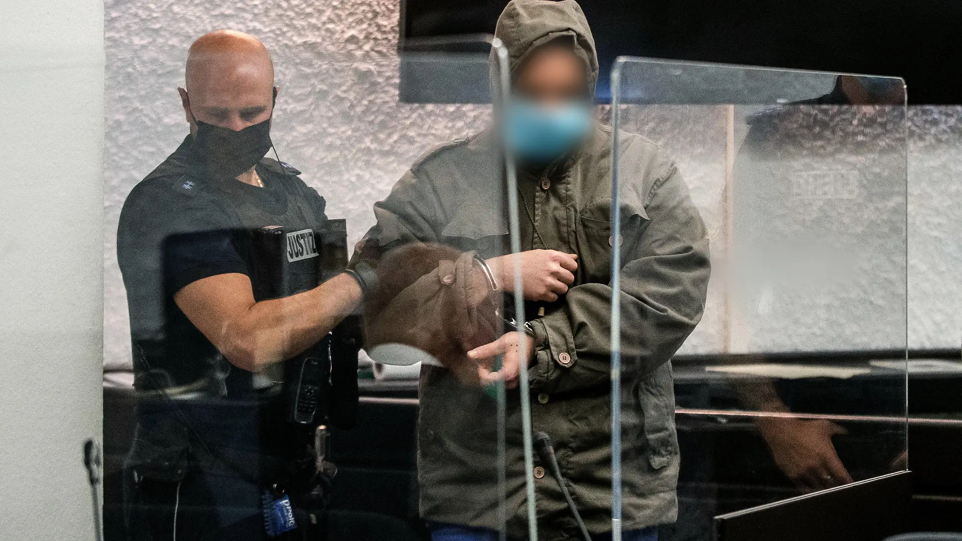 14.10.2022, Baden-Württemberg, Stuttgart: Ein Justizbeamter führt in einem Gerichtssaal des Landgerichts Stuttgart einen Angeklagten zu seinem Platz. Dem Angeklagten wird vorgeworfen, im April 2022 eine Frau auf einem Feldweg in Reichenbach an der Fils überfallen und sie in einer in der Nähe gelegenen Hütte 24 Stunden lang vergewaltigt zu haben. Foto: Christoph Schmidt/dpa - Nutzung nur nach schriftlicher Vereinbarung mit der dpa +++ dpa-Bildfunk +++