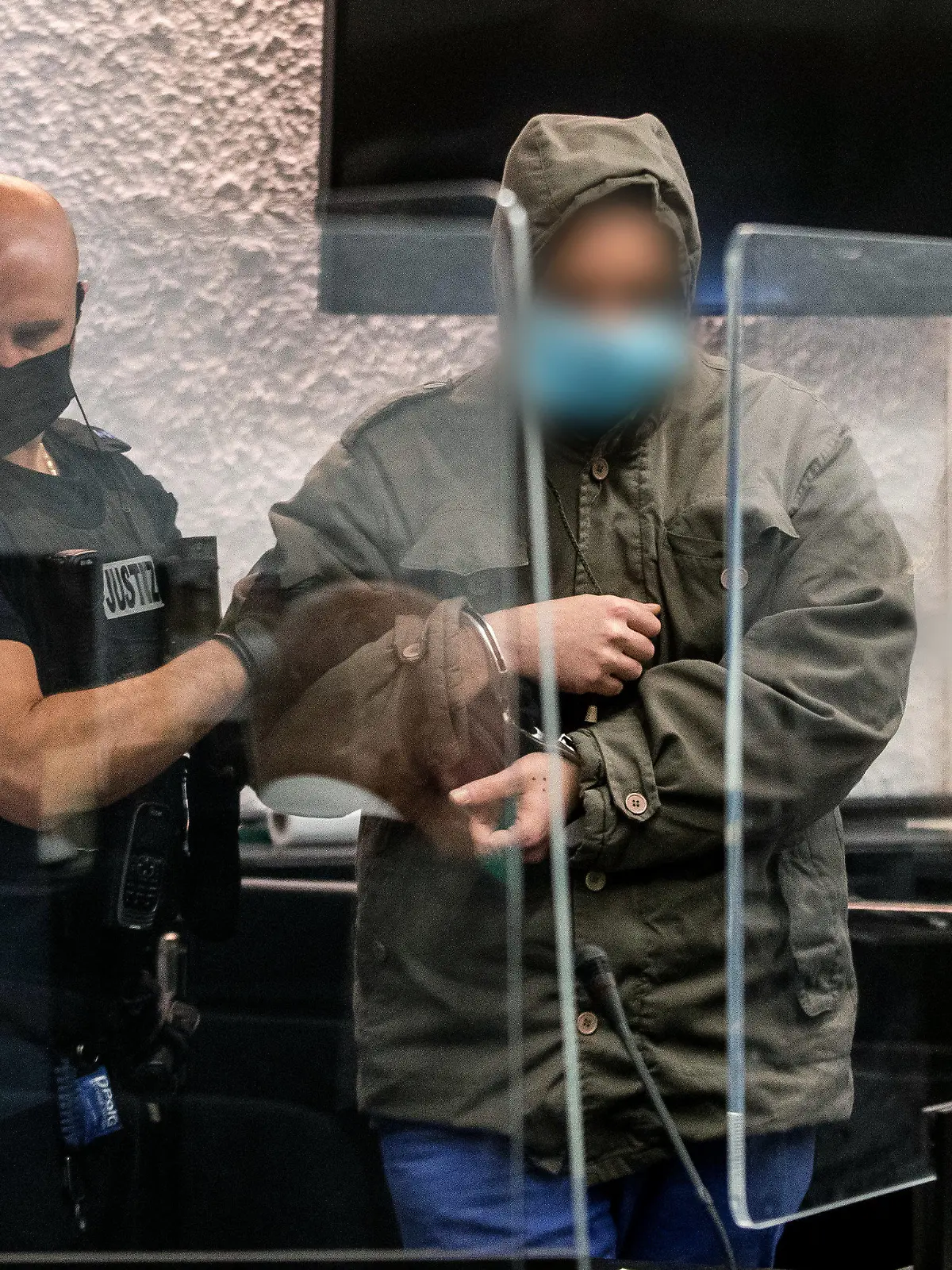 14.10.2022, Baden-Württemberg, Stuttgart: Ein Justizbeamter führt in einem Gerichtssaal des Landgerichts Stuttgart einen Angeklagten zu seinem Platz. Dem Angeklagten wird vorgeworfen, im April 2022 eine Frau auf einem Feldweg in Reichenbach an der Fils überfallen und sie in einer in der Nähe gelegenen Hütte 24 Stunden lang vergewaltigt zu haben. Foto: Christoph Schmidt/dpa - Nutzung nur nach schriftlicher Vereinbarung mit der dpa +++ dpa-Bildfunk +++
