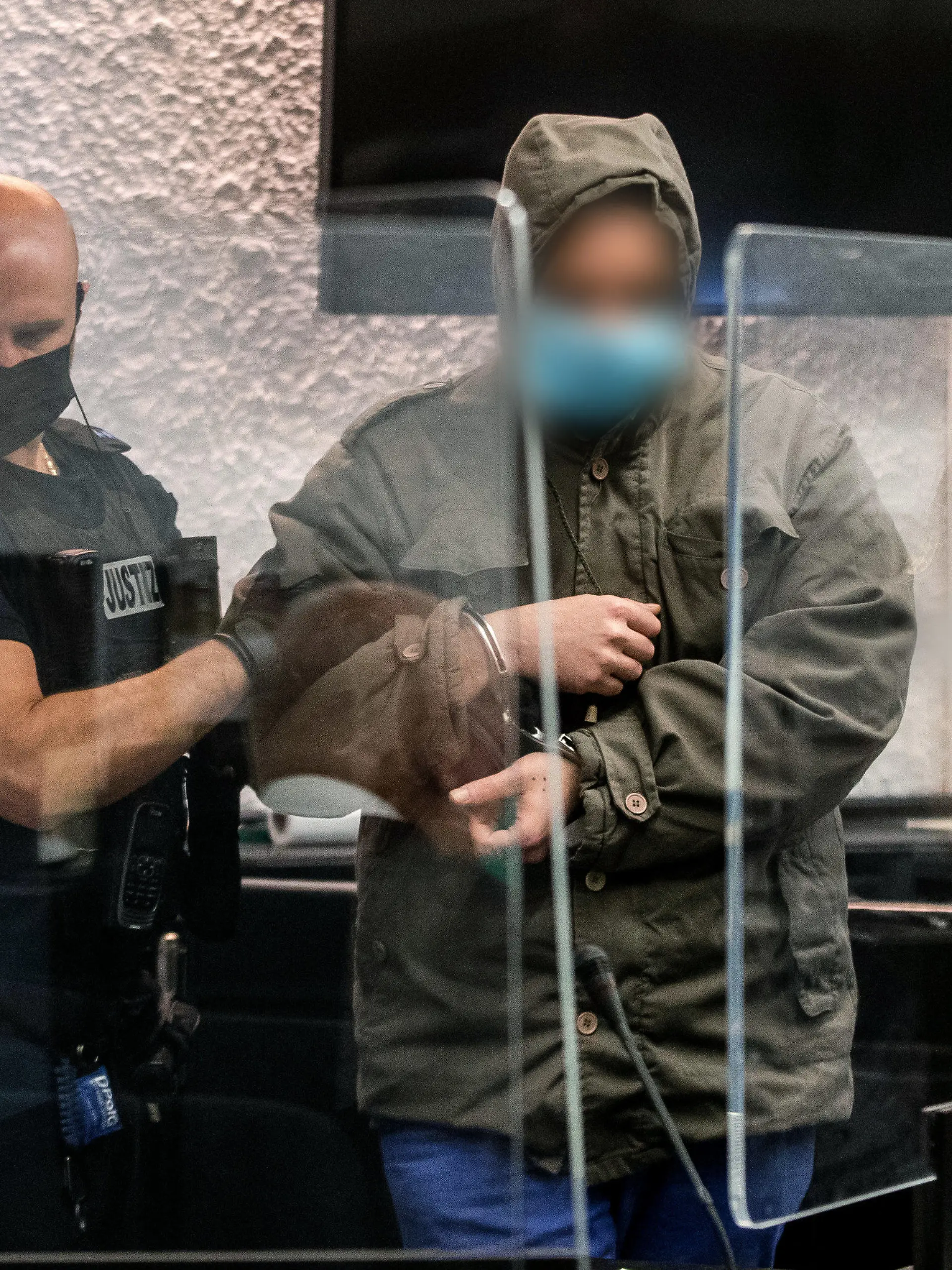 14.10.2022, Baden-Württemberg, Stuttgart: Ein Justizbeamter führt in einem Gerichtssaal des Landgerichts Stuttgart einen Angeklagten zu seinem Platz. Dem Angeklagten wird vorgeworfen, im April 2022 eine Frau auf einem Feldweg in Reichenbach an der Fils überfallen und sie in einer in der Nähe gelegenen Hütte 24 Stunden lang vergewaltigt zu haben. Foto: Christoph Schmidt/dpa - Nutzung nur nach schriftlicher Vereinbarung mit der dpa +++ dpa-Bildfunk +++