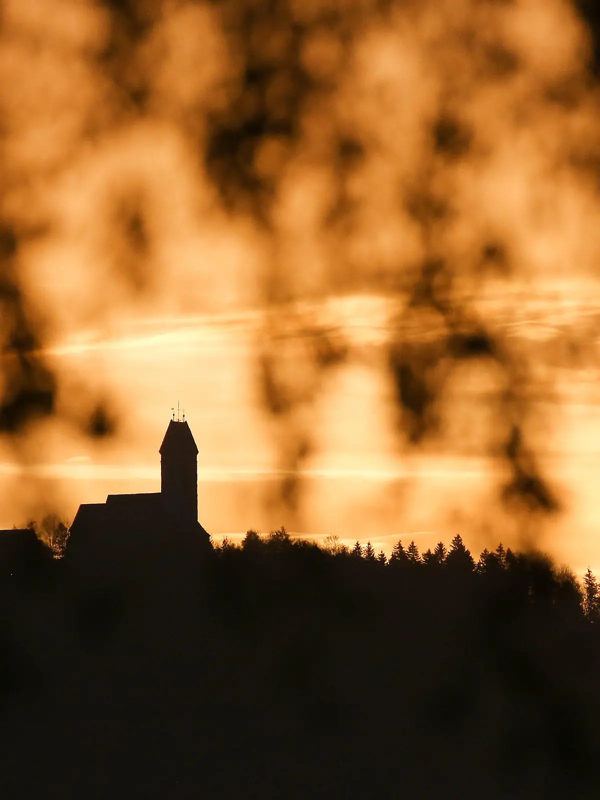 28.10.2022, Baden-Württemberg, Riedlingen: Hinter dem Berg Bussen mit seiner Wallfahrtskirche hat sich am Morgen der Himmel durch die Sonne und Saharastaub, der in der Luft liegt, gelblich gefärbt. Foto: Thomas Warnack/dpa +++ dpa-Bildfunk +++