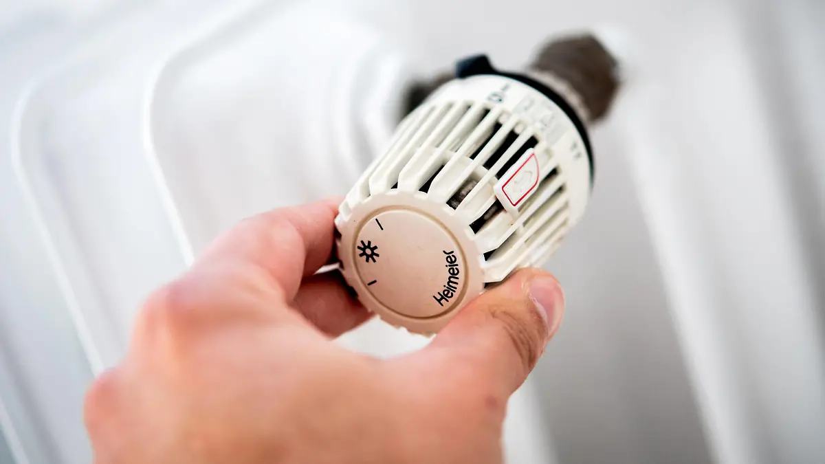 ARCHIV - 04.10.2021, Niedersachsen, Hannover: Ein Mann dreht in einer Wohnung am Thermostat einer Heizung. (zu dpa: "Bundesregierung bringt Soforthilfe für Gaskunden auf den Weg") Foto: Hauke-Christian Dittrich/dpa +++ dpa-Bildfunk +++