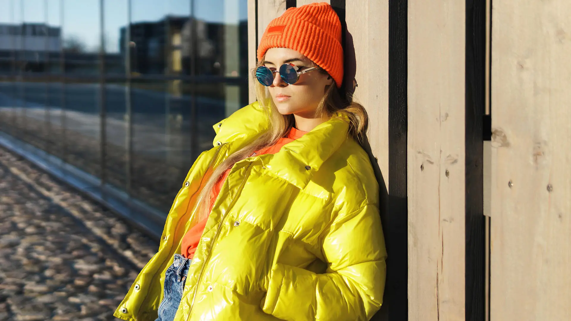 Portrait of stylish girl wearing yellow puffer and orange knitted hat