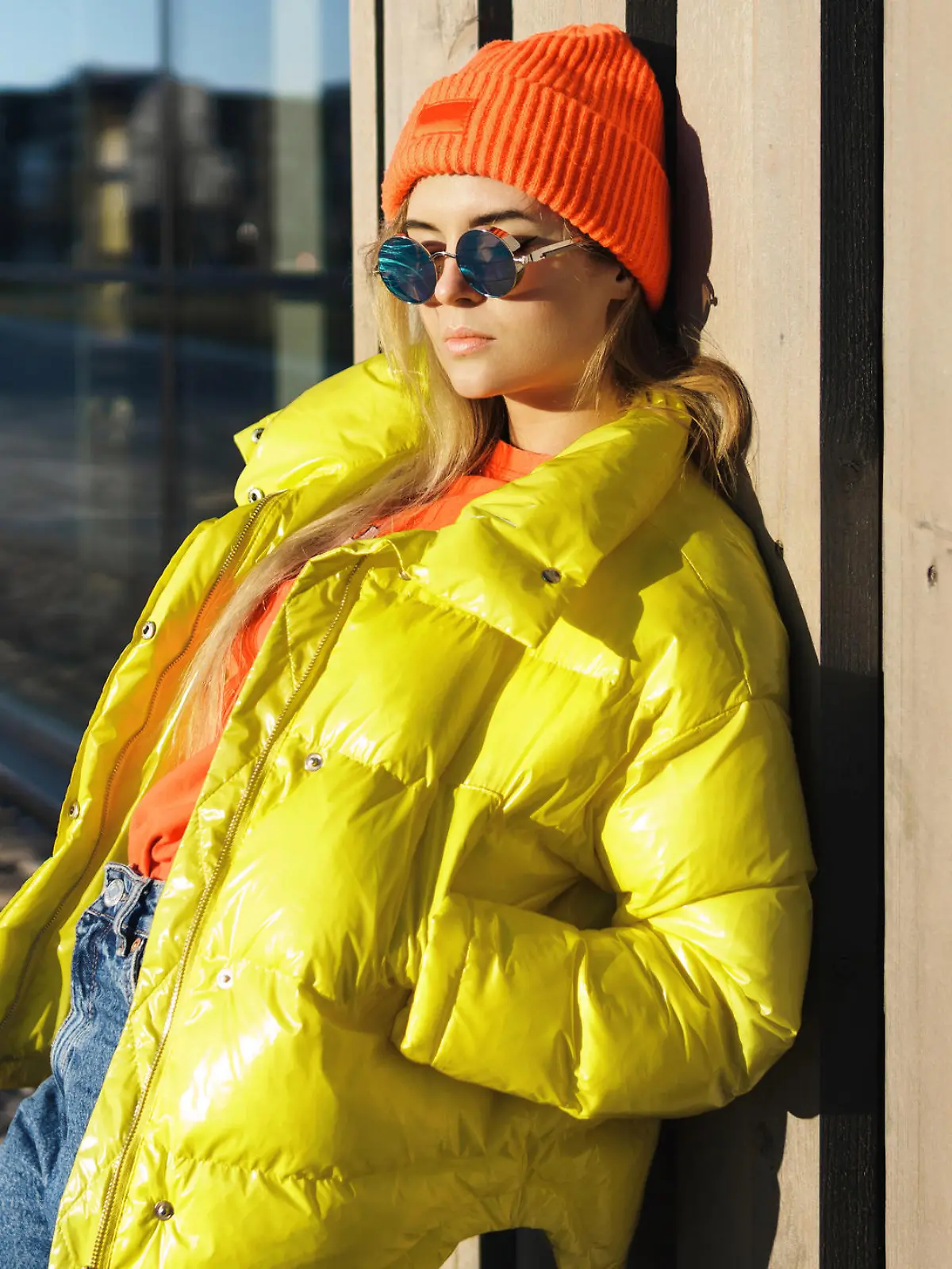 Portrait of  stylish girl wearing yellow puffer and orange knitted hat
