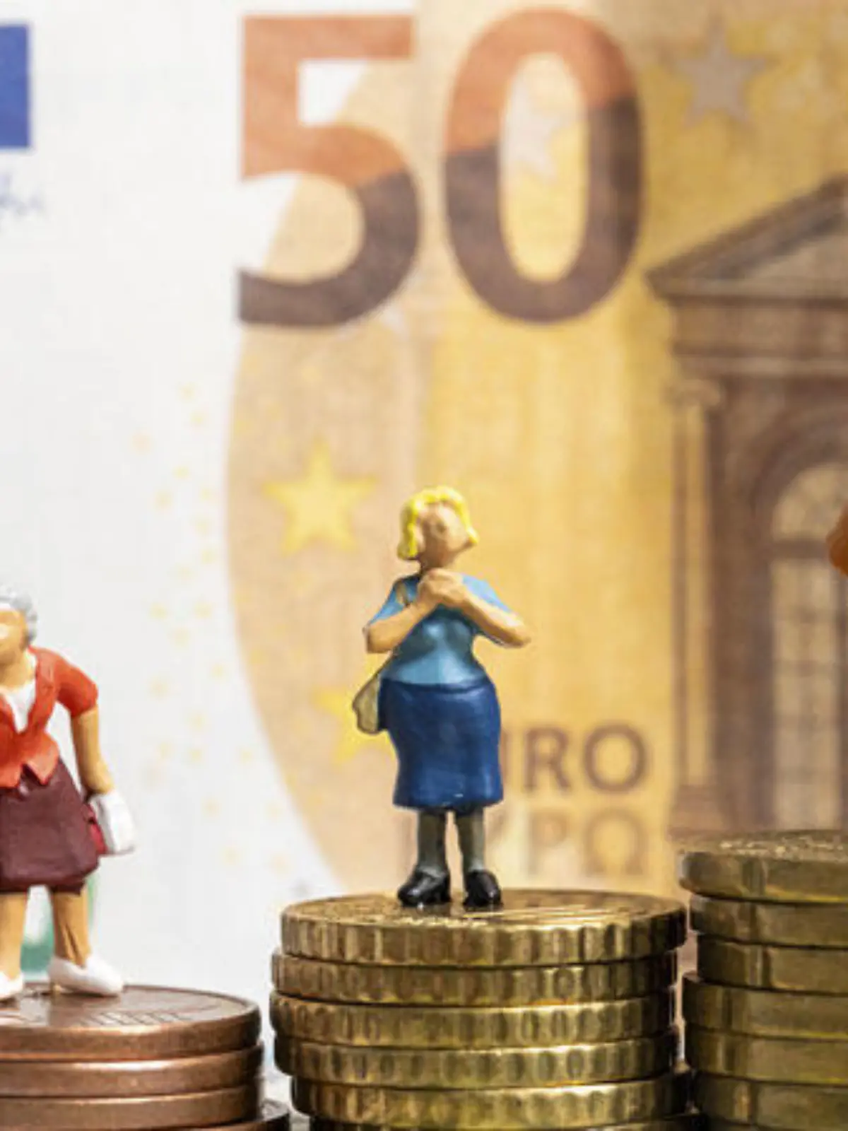 Miniaturfiguren auf Euro Geldmünzen umgeben von Euro Bargeld Scheinen. Symbolbild Rente und Finanzen im Alter