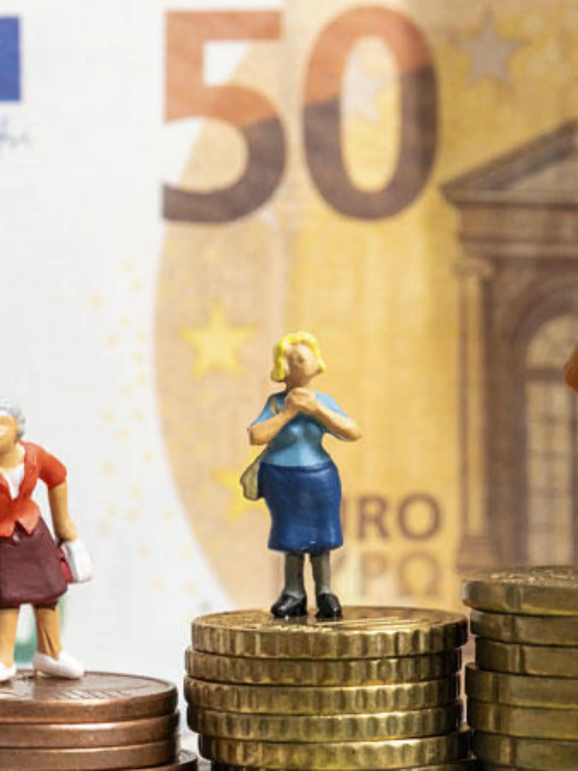 Miniaturfiguren auf Euro Geldmünzen umgeben von Euro Bargeld Scheinen. Symbolbild Rente und Finanzen im Alter