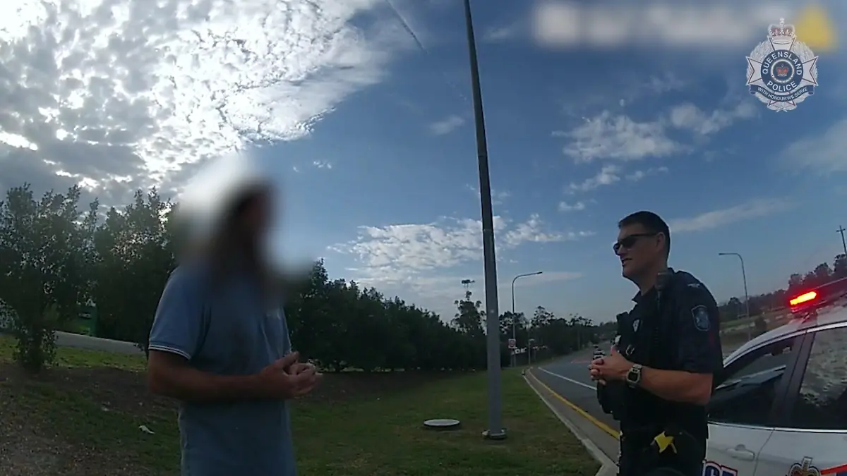 SCREENSHOT - 21.11.2023, Australien, Coomera: HANDOUT - Dieses Videostandbild von der Polizei Queensland zeigt einen 43-jährigen Mann, der mit der Polizei spricht. Um das Geld für ein Taxi zu sparen und 50 Kilometer gratis mitzufahren, hat sich ein betrunkener Australier auf dem Unterbau eines Lastwagens eingepfercht. Der Truck war ohne Zwischenstopp auf dem Weg in einen anderen Bundesstaat. Am Ende musste der Mann rund 400 Kilometer in prekärer Position auf dem Metallgestell ausharren - nur einen halben Meter über der Fahrbahn hängend. Foto: Queensland Police/QUEENSLAND POLICE/AP/dpa - ACHTUNG: Verwendung nur im vollen Format und vollständigen Credti +++ dpa-Bildfunk +++