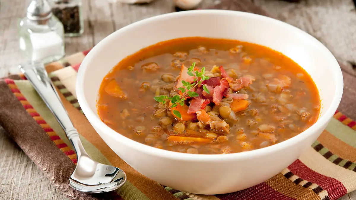 Closeup of a bowl of lentil soup garnished with bacon and fresh thyme.Related Images: