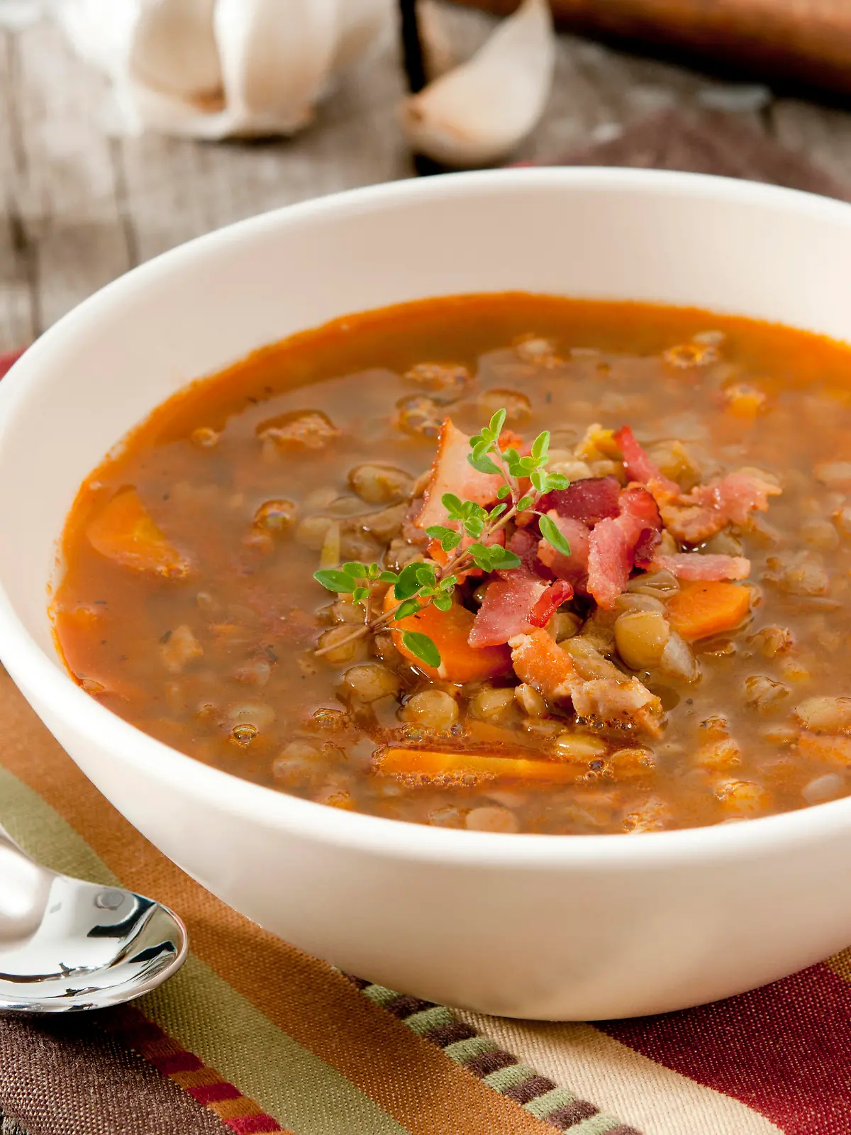 Closeup of a bowl of lentil soup garnished with bacon and fresh thyme.Related Images:
