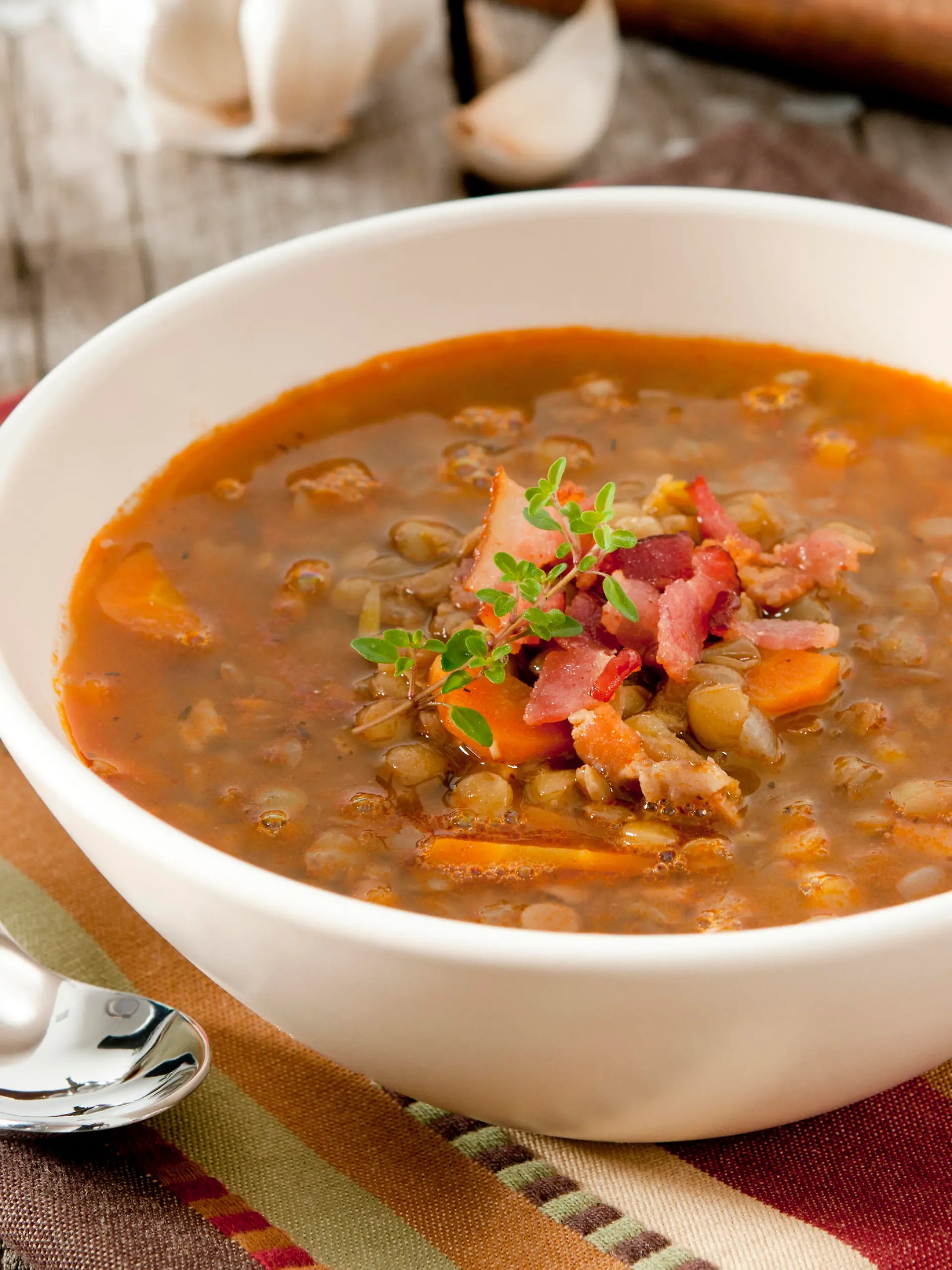 Closeup of a bowl of lentil soup garnished with bacon and fresh thyme.Related Images: