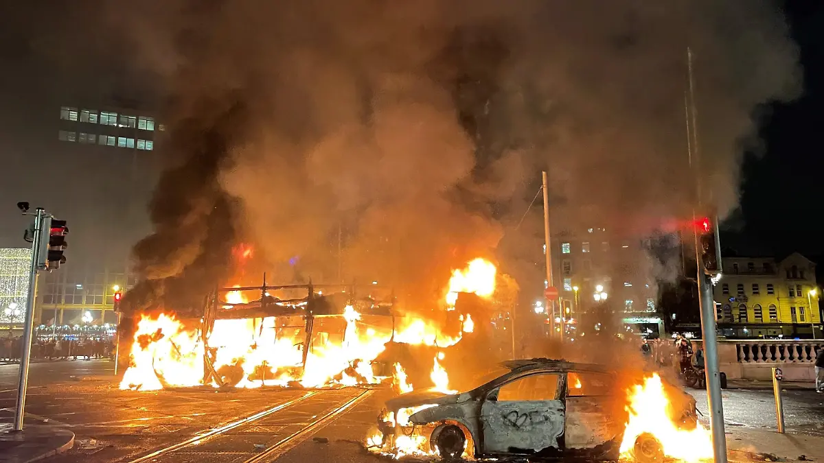 23.11.2023, Irland, Dublin: Ein Bus und ein Auto brennen in der O'Connell Street im Stadtzentrum von Dublin. Nach einem Messerangriff in der irischen Hauptstadt, bei dem unter anderem ein fünfjähriges Mädchen und eine Frau schwer verletzt wurden, kam es am Abend in der Nähe des Tatorts zu schweren Ausschreitungen. Foto: Brian Lawless/PA Wire/dpa +++ dpa-Bildfunk +++
