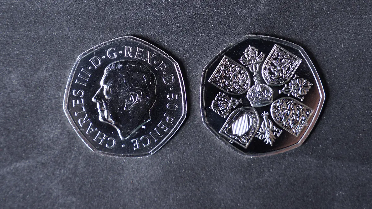 28.10.2022, Großbritannien, Pontyclun: Eine Geldmünze mit dem Konterfei des britischen König Charles III. (l) liegt neben einer Geldmünze, auf der die Rückseite abgebildet ist. Die ersten britischen Geldmünzen mit dem Konterfei des neuen Königs Charles III. kommen in den Umlauf. Die Münzprägeanstalt Royal Mint hat an ihrem Sitz im walisischen Llantrisant mit der Produktion von 50-Pence-Stücken begonnen. Foto: Alistair Heap/PA Wire/dpa - ACHTUNG: Nur zur redaktionellen Verwendung im Zusammenhang mit der aktuellen Berichterstattung und nur mit vollständiger Nennung des vorstehenden Credits +++ dpa-Bildfunk +++