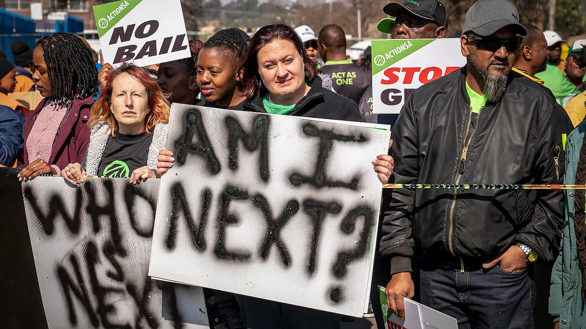 Women protest outside the Krugersdorp, South Africa, Magistrates Court Monday, Aug. 1, 2022. More than 80 men suspected of the gang rapes of eight women and armed robbery of a video production crew in the ming town, west of Johannesburg appeared in court on Monday. (AP Photo/Shiraaz Mohamed)