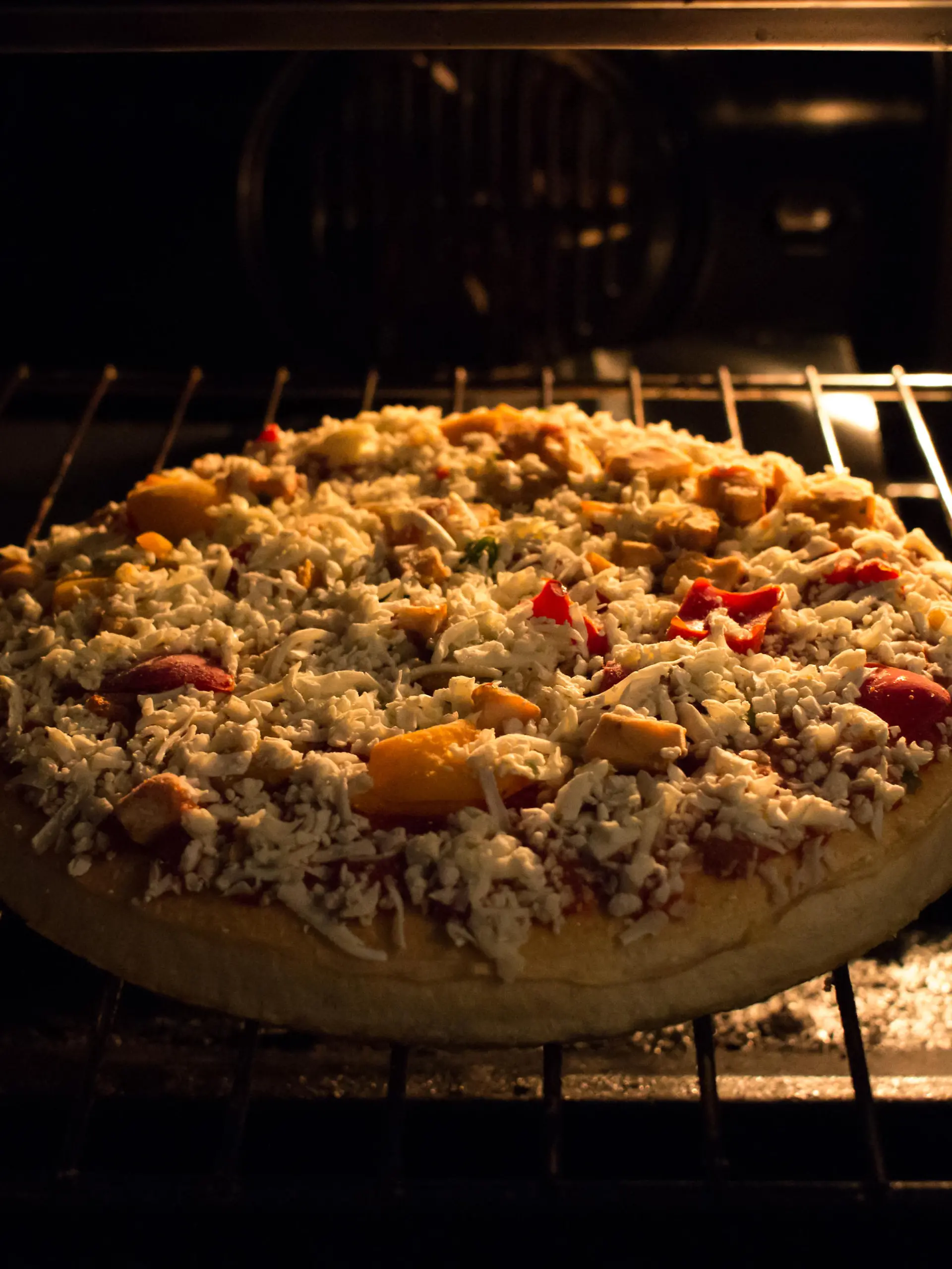 A frozen pizza just went in the hot oven, still frozen and almost ready to eat.