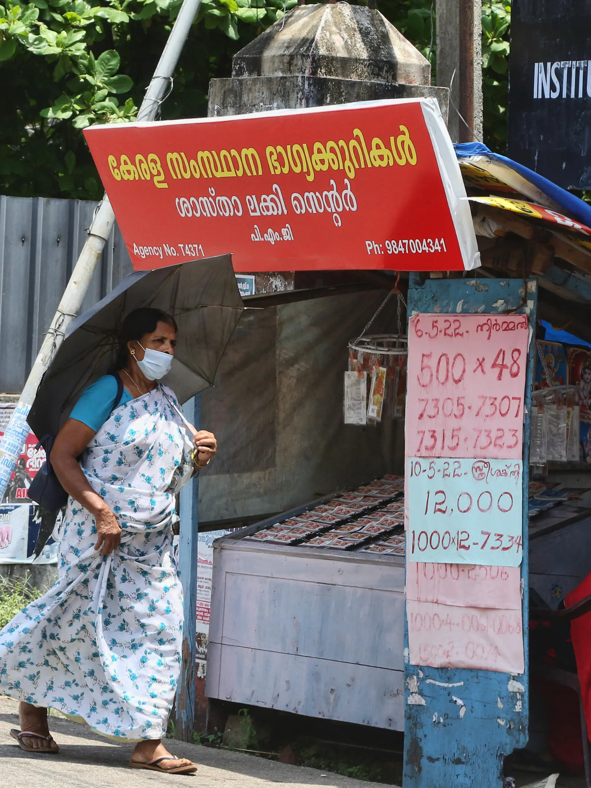 Woman walks past a small stand selling lottery tickets along the roadside in the city of Thiruvananthapuram (Trivandrum), Kerala, India on May 12, 2022. (Photo by Creative Touch Imaging Ltd./NurPhoto)