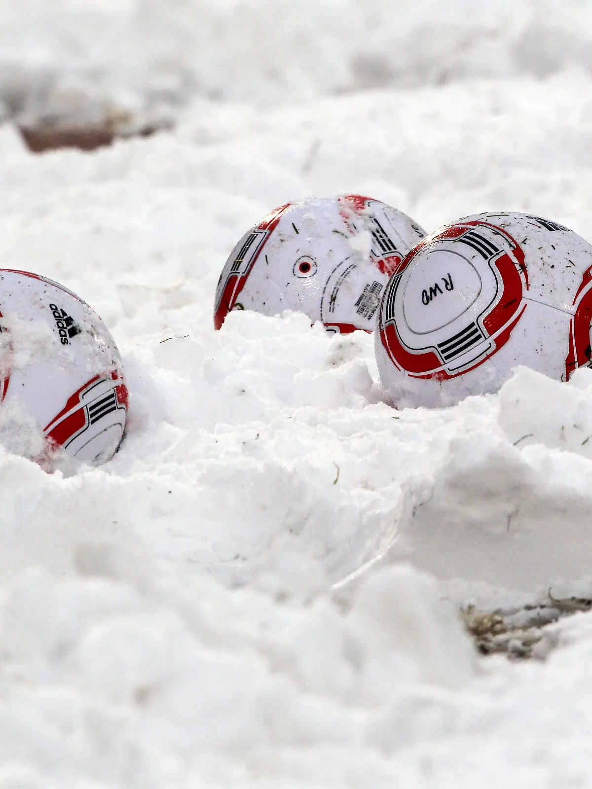 ARCHIV - Fußbälle liegen am 19.12.2010 bei der Zweitligabegegnung SC Rot-Weiß Oberhausen - FC Energie Cottbus im Oberhausener Niederrhein-Stadion im Schnee. Eis und Schnee haben den Fans die Lust auf Fußball im Winter gründlich verdorben. Mehr als die Hälfte der Fußball- Anhänger ist für eine Umstellung der Saison auf das Kalenderjahr mit Start im März und Meister-Kür im November. Foto: Roland Weihrauch dpa (zu dpa-Umfrage: "Wintermüde Fußball-Fans für anderen Spielplan" vom 23.12.2010)  +++(c) dpa - Bildfunk+++