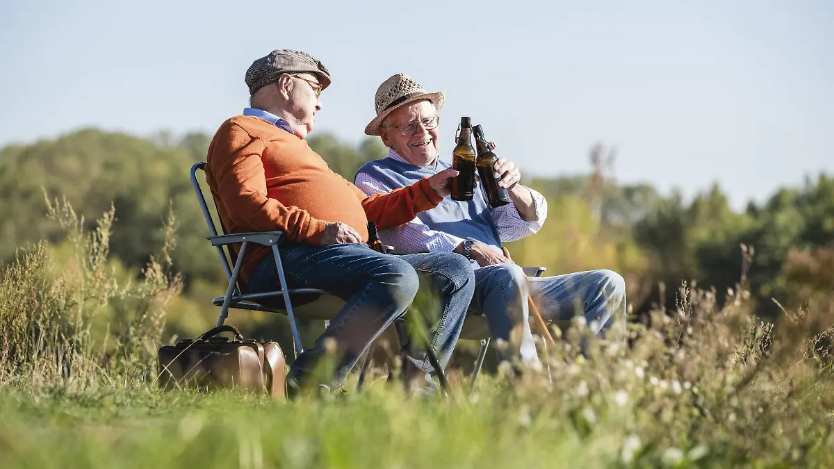 Two old friends sitting in the fields, drinking beer, talking about old times model released Symbolfoto PUBLICATIONxINxGERxSUIxAUTxHUNxONLY UUF15478  