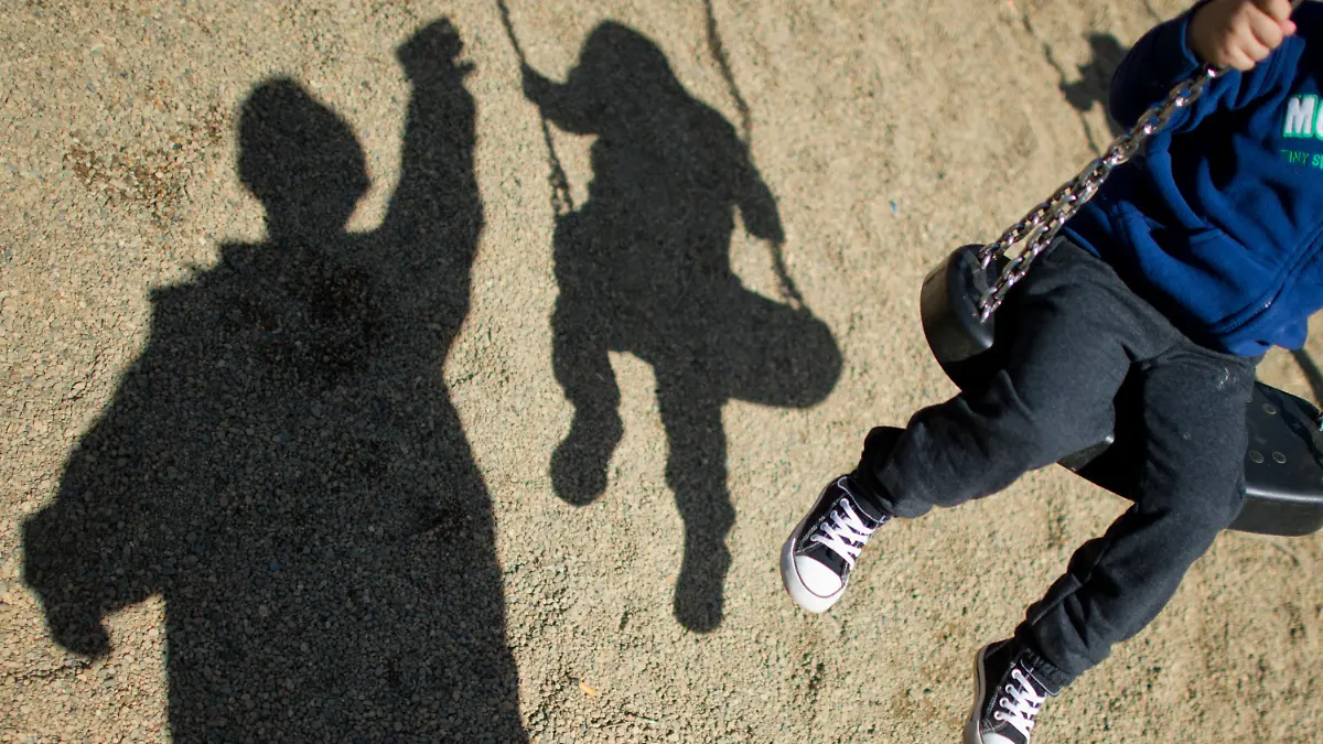 ARCHIV - 27.08.2014, Niedersachsen, Braunschweig: Der Schatten eines Mannes und eines schaukelnden Kindes fallen auf einem Spielplatz. Sich draußen austoben - das können nicht alle Kinder direkt vor ihrer Tür. Doch manchmal scheitert es auch an den Eltern. Sie meinen es gut, bewirken aber das Gegenteil. Foto: Julian Stratenschulte/dpa +++ dpa-Bildfunk +++
