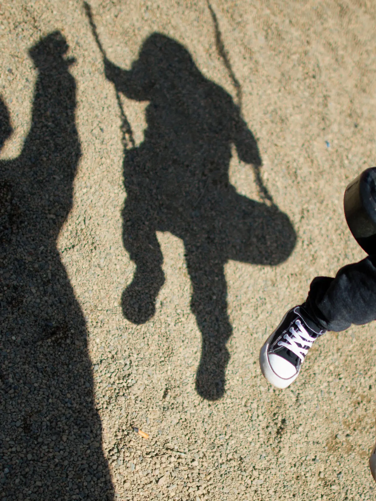ARCHIV - 27.08.2014, Niedersachsen, Braunschweig: Der Schatten eines Mannes und eines schaukelnden Kindes fallen auf einem Spielplatz. Sich draußen austoben - das können nicht alle Kinder direkt vor ihrer Tür. Doch manchmal scheitert es auch an den Eltern. Sie meinen es gut, bewirken aber das Gegenteil. Foto: Julian Stratenschulte/dpa +++ dpa-Bildfunk +++