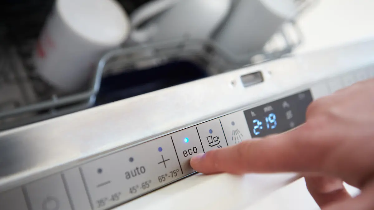 Close Up Of Man Setting Economy Cycle On Dishwasher