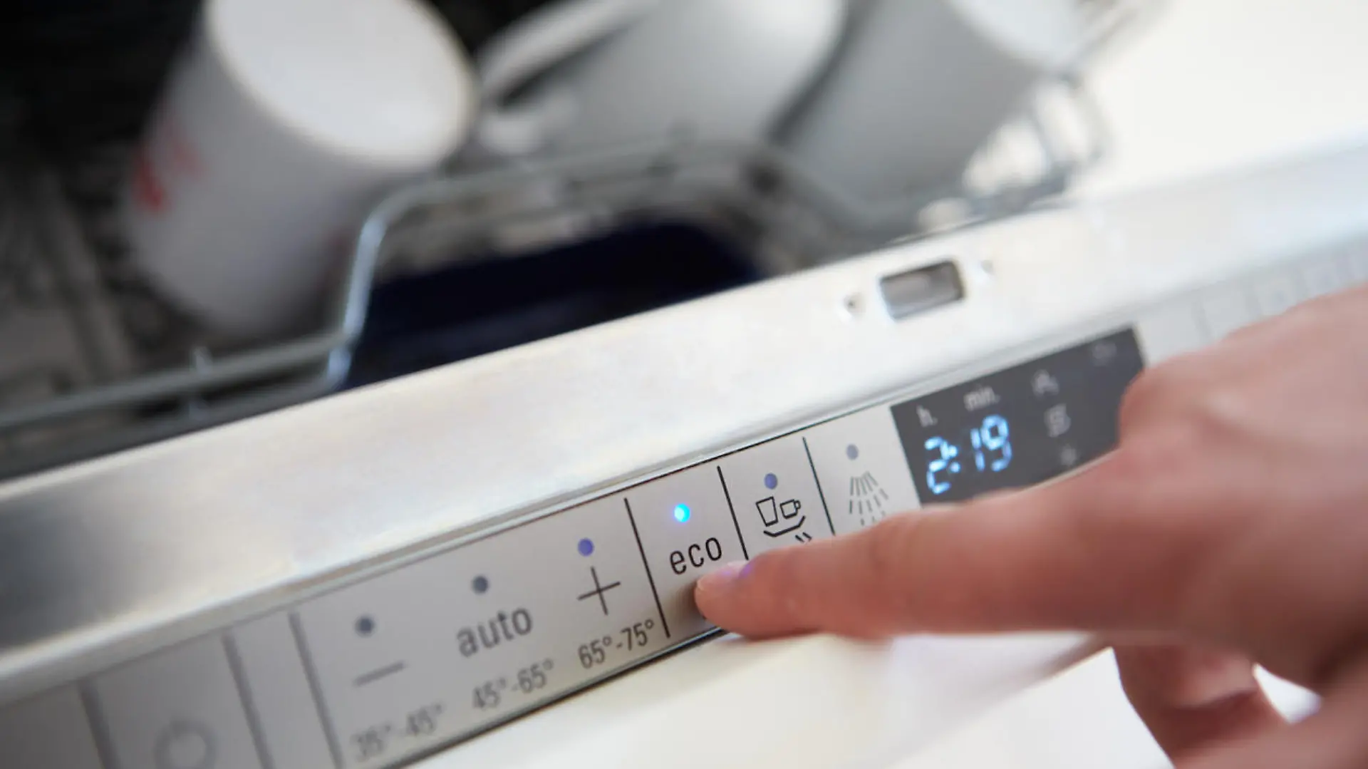 Close Up Of Man Setting Economy Cycle On Dishwasher