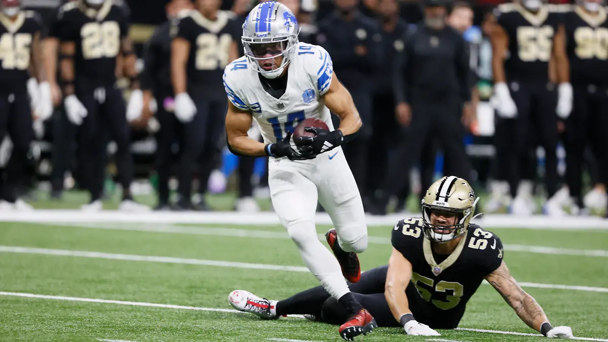 03.12.2023, USA, New Orleans: American Football: Profiliga NFL, New Orleans Saints - Detroit Lions, Hauptrunde, Hauptrunde-Partien, 13. Spieltag, Mercedes-Benz Superdome: Detroit Lions Wide Receiver Amon-Ra St. Brown (vorne) fängt einen 25-Yard-Pass für einen Touchdown während der ersten Hälfte des Spiels; rechts am Boden: New Orleans Saints Linebacker Zack Baun. Foto: Butch Dill/FR111446 AP/dpa +++ dpa-Bildfunk +++